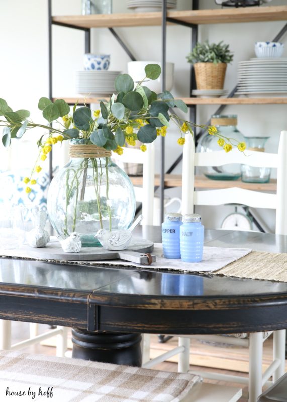 Blue salt and pepper shakers on table with yellow flowers in a jar.