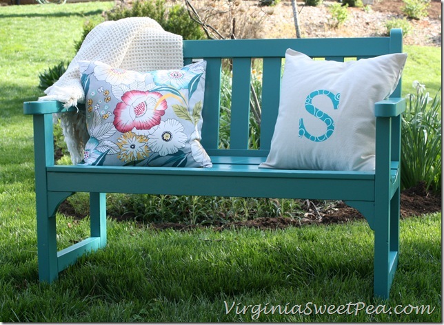 A wooden outdoor bench painted a blue/teal colour.