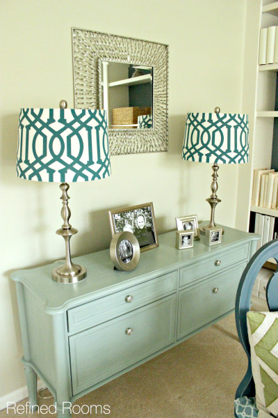 A mint colour painted dresser with white and teal lampshades.