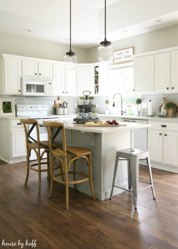 Neutral white kitchen with pendant lights above island.