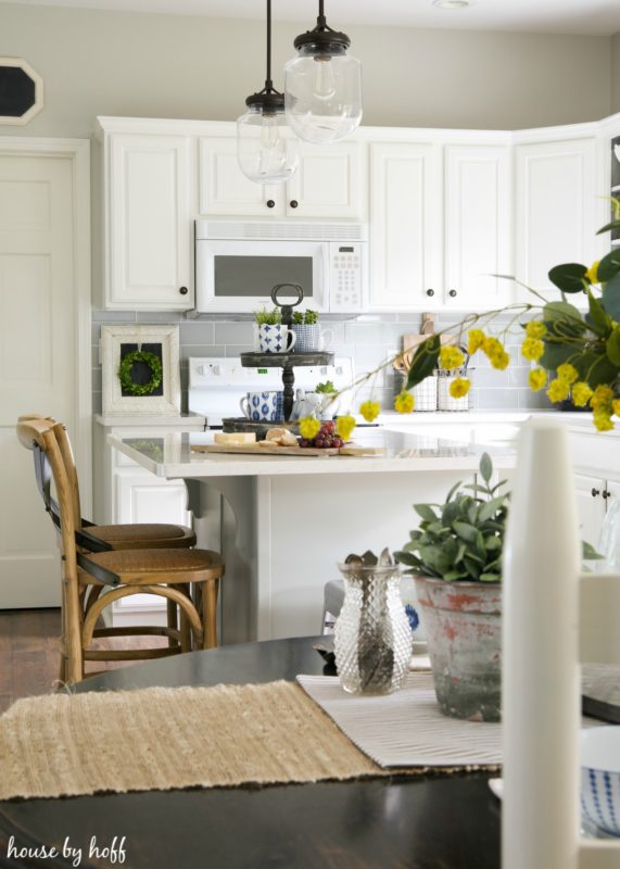 Yellow flowers on counter and light wicker bar chairs by island.