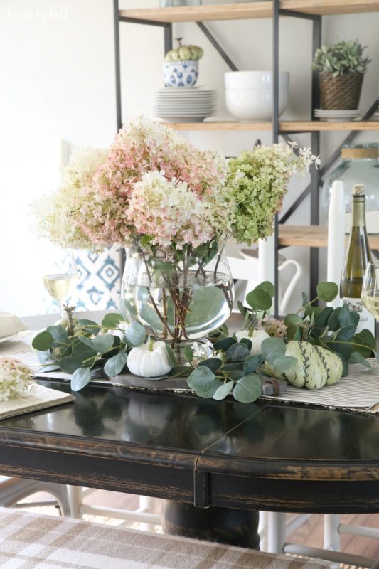 White and pink hydrangeas on table in glass vase.