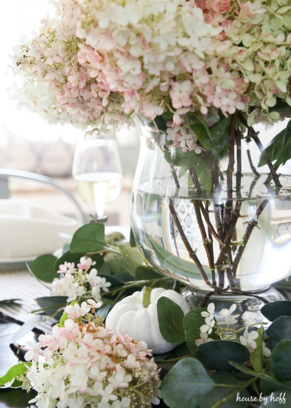 White and pink hydrangeas in vase on fall table setting.