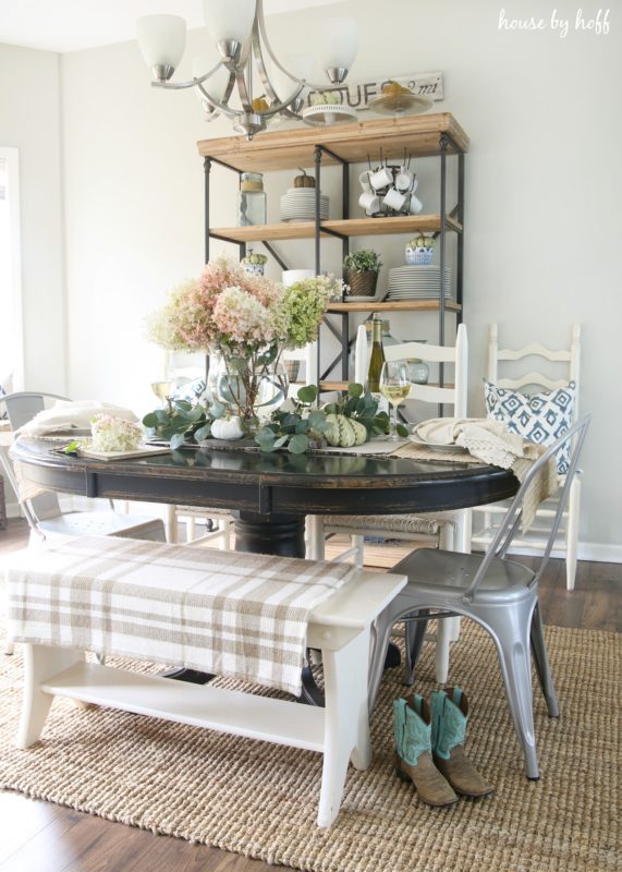 Wooden table and white bench in dining room with fall flowers on it.