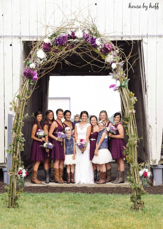 Twig and flower arch with bride and bridesmaids under it.