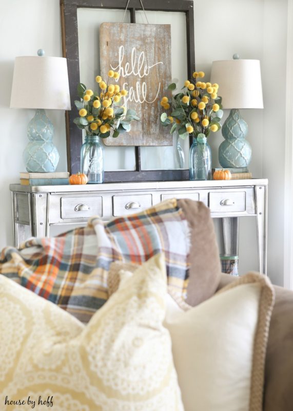 Pewter side table with hello fall poster and yellow flowers in glass mason jars.