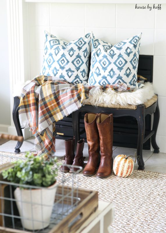 Cowboy boots, a pumpkin in front of bench on the floor.