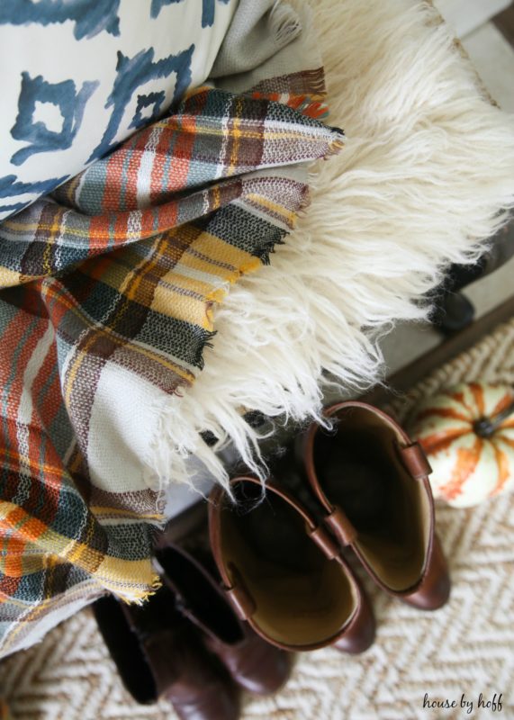 Faux fur, plaid and blue and white pillows on bench.