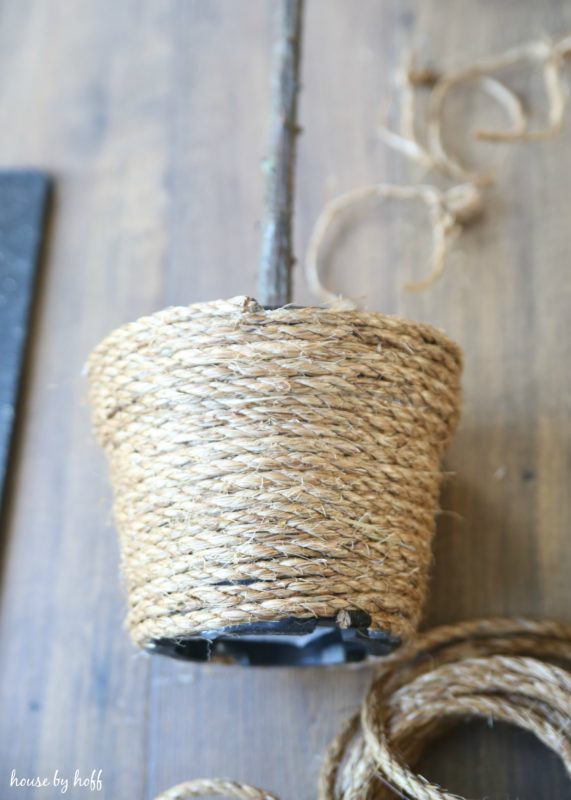 The base of the topiary being wrapped by rope.