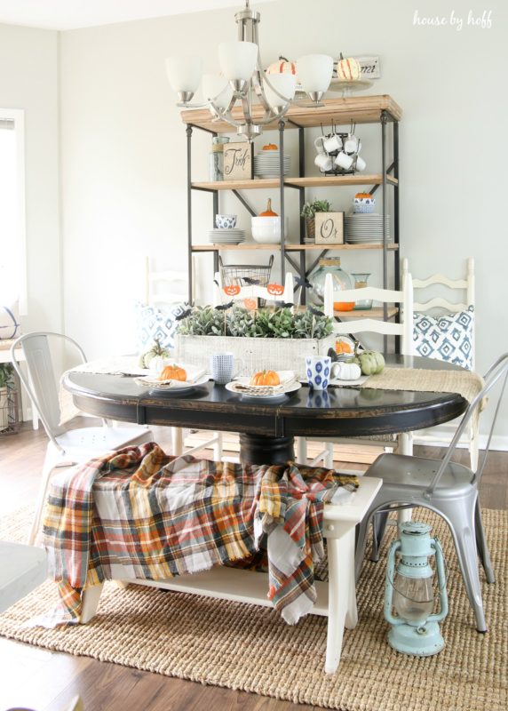 Wooden dining room table with orange, green and white pumpkins on table.