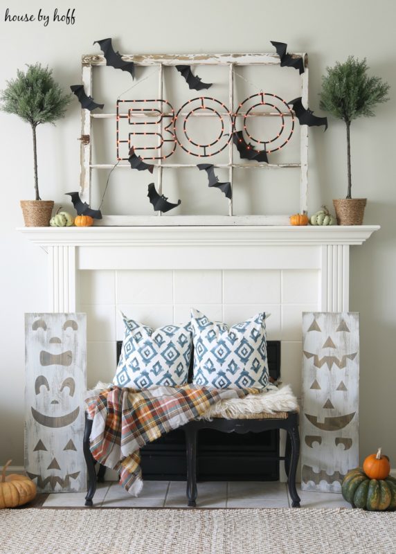 Halloween Mantel with wooden bench in front of it and blue and white pillows on it.