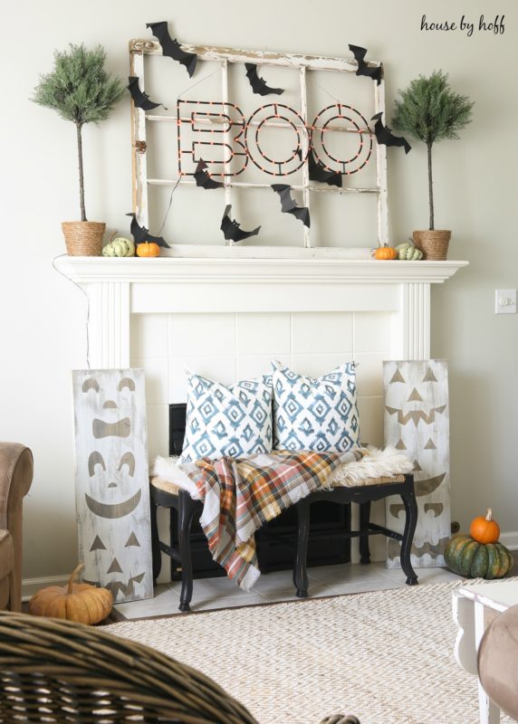 Pumpkin wooden jack'o'lantern signs in front of fireplace.