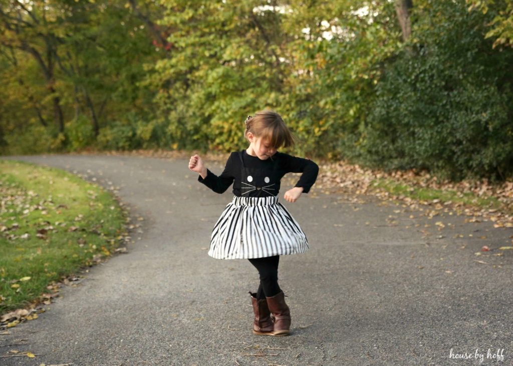 Little girl in black and white cat costume in the middle of the road posing.