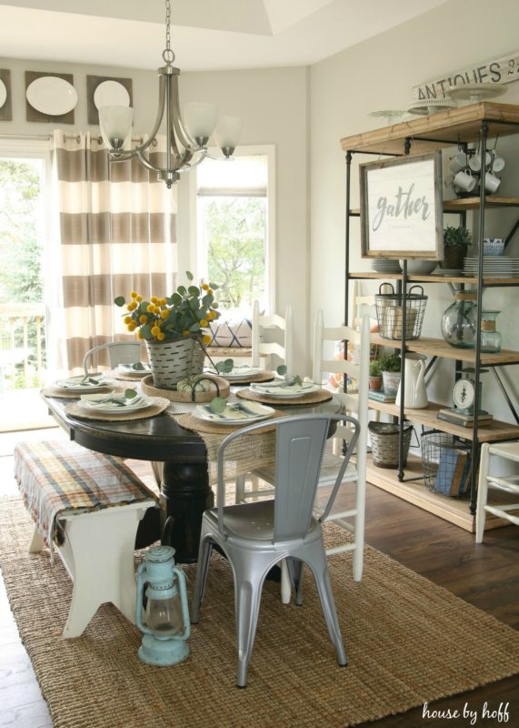 Wooden dining room table with bench chair sitting on a sisal rug.