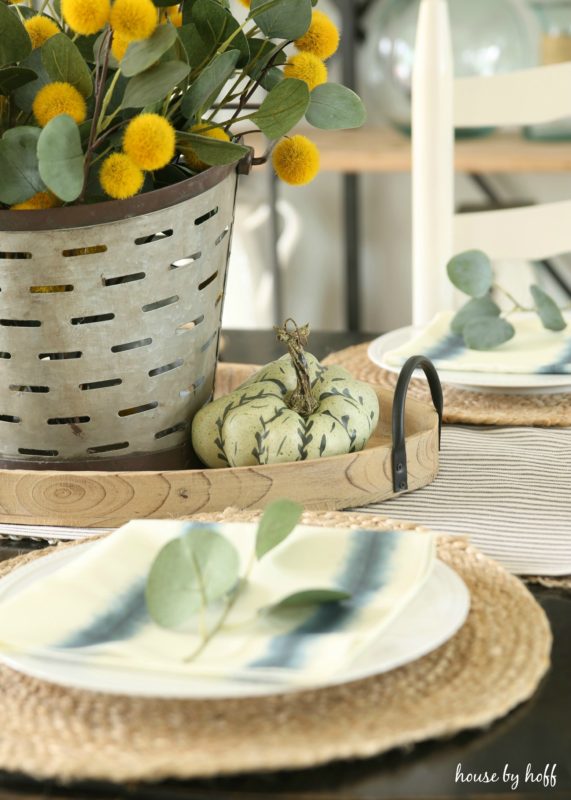 Green and white mini pumpkin beside plate on table.