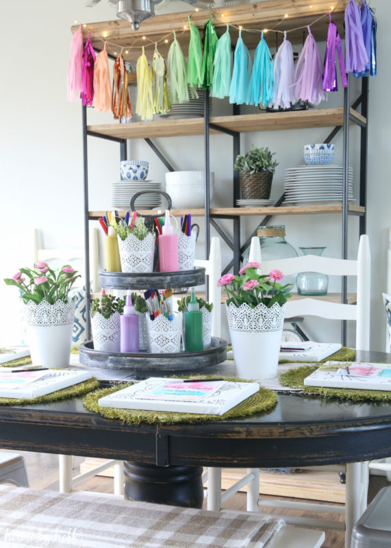 White planters with pink flowers on table.