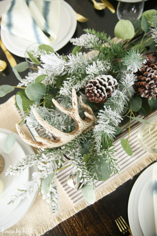 Centerpiece with antlers, pine cones, and greenery.