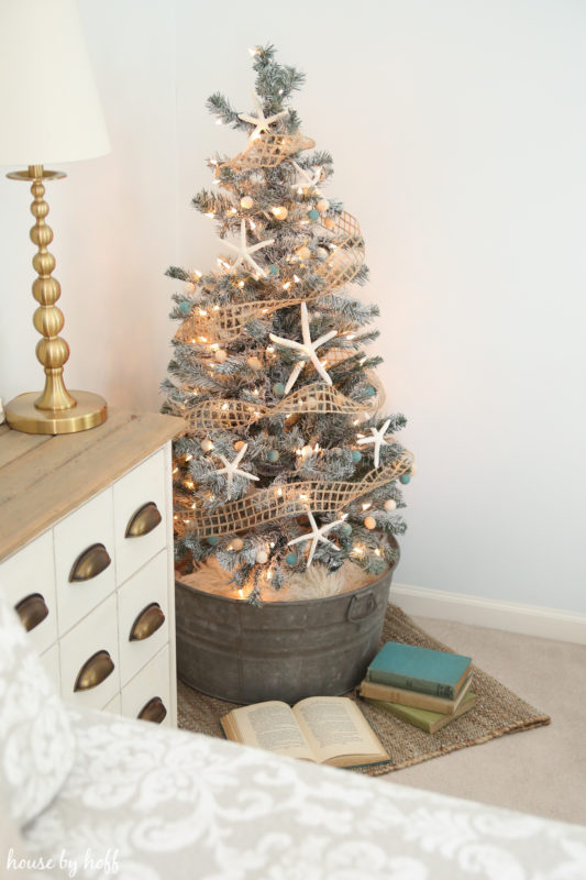 The decorated flocked tree in a galvanized bucket in the corner of the room.