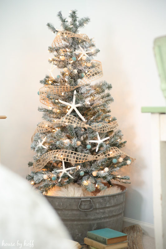 Christmas tree in a galvanized bucket, with antique books in front of it.