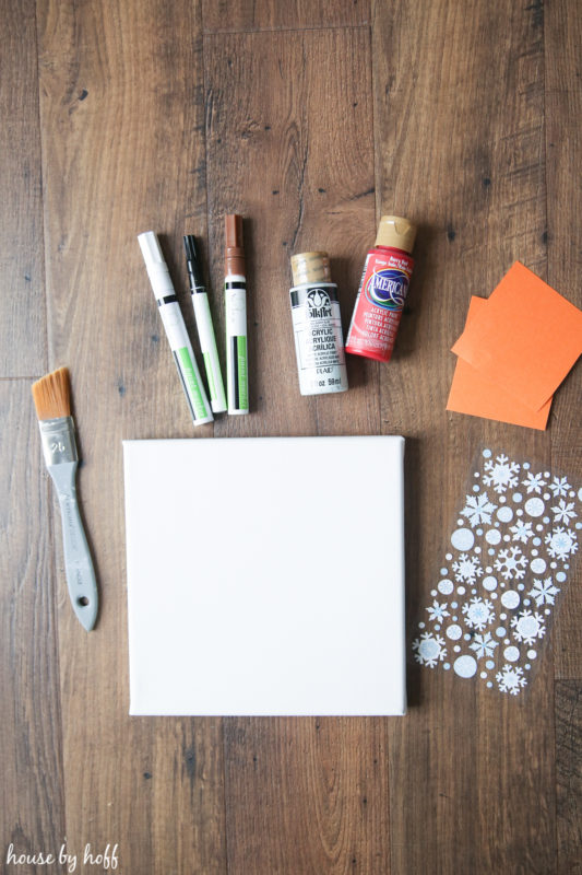 Paint, a brush, a canvas, and snowflake stickers.