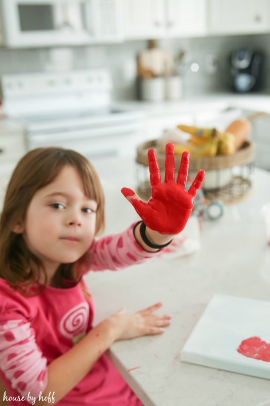 Little girl with a painted red hand.