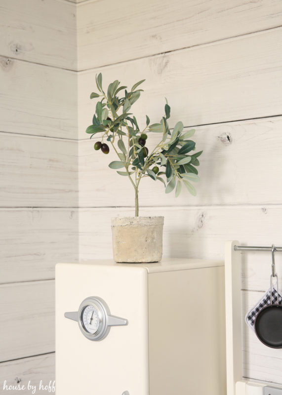 Little white play fridge with plant on top of it.