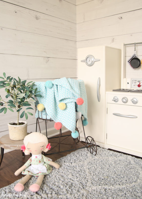 A small play stove and a doll in the play kitchen.