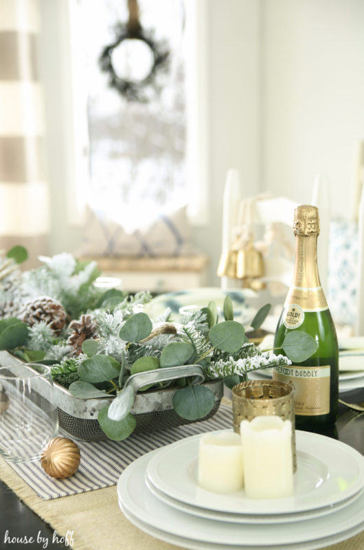 Bottle of champagne and candles on dining room table.