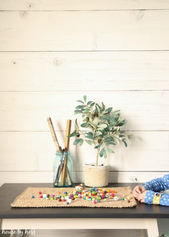 Table with plant and beads on it in front of shiplap wall.