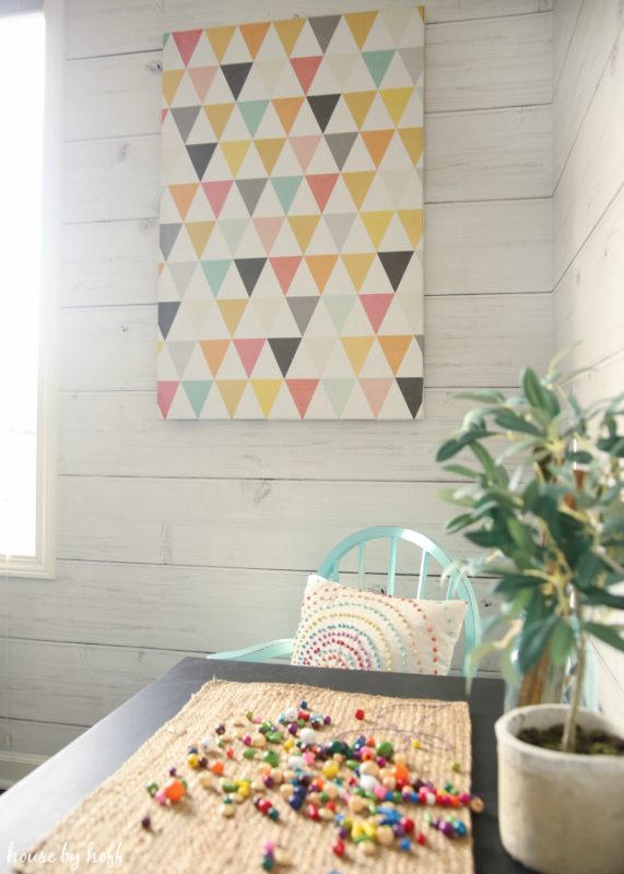 Multi colored beads on the table and a graphic print on the wall in the playroom.