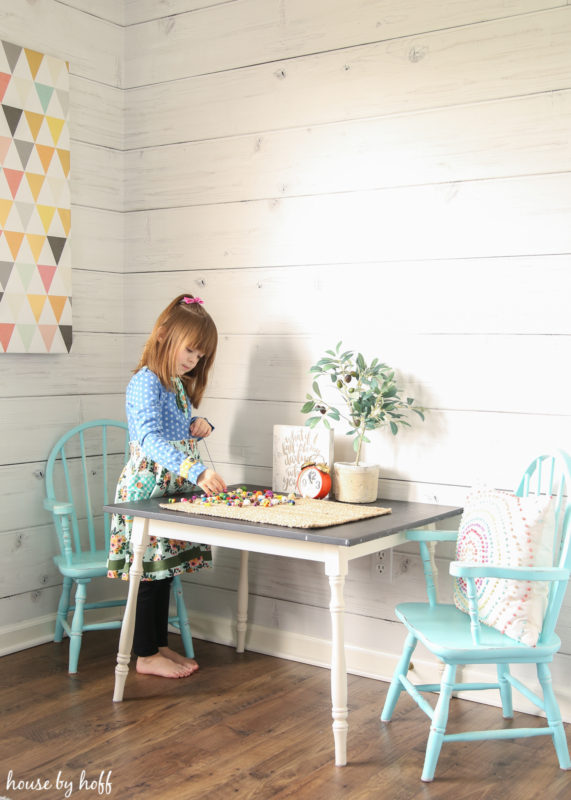 A small child standing by the table in the modern farmhouse playroom.