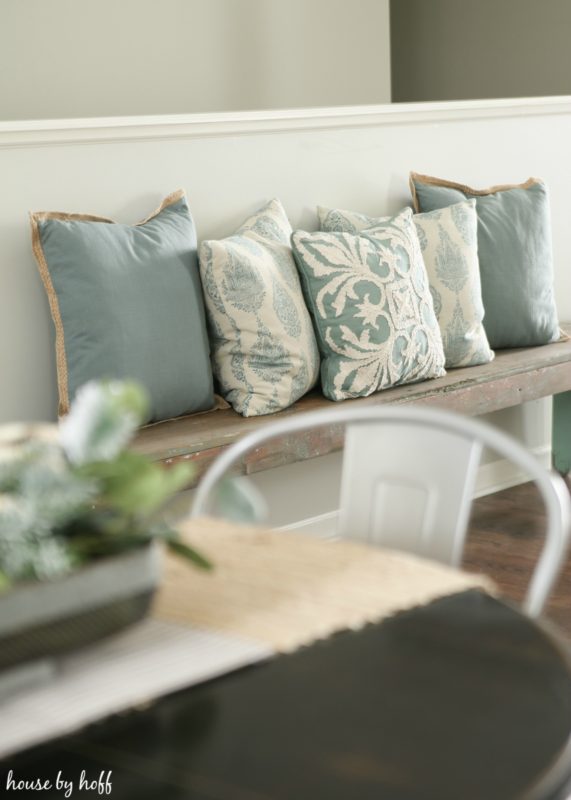 Blue and white throw pillows on wooden bench.