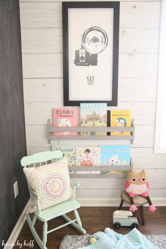 A mint green rocking chair beside the bookshelf in the playroom reading nook.