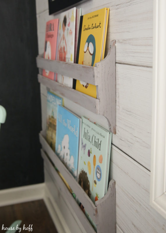 The painted bookshelves on the wall with children's books in them.