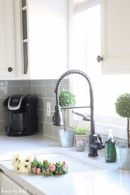 A farmhouse sink with flowers in the sink.