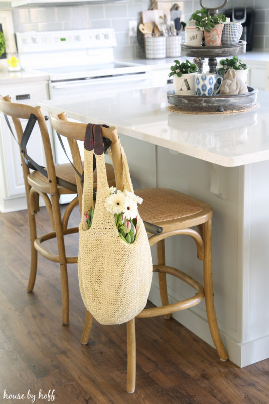 A tray on the white kitchen island filled with little plants and mugs.