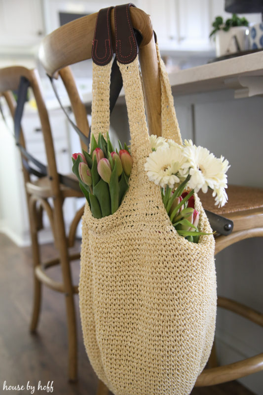 Up close of the flowers in a bag on the back of a chair.