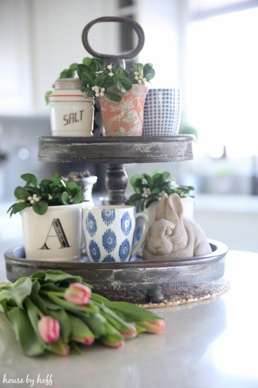 A tiered tray with tulips beside it.