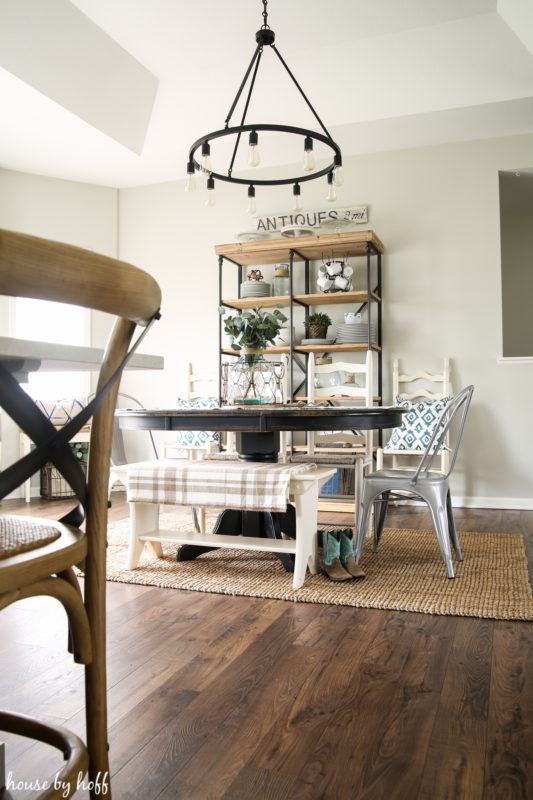 The dining room with dark wood laminate floors and a modern farmhouse light fixture above the wooden dining room table.