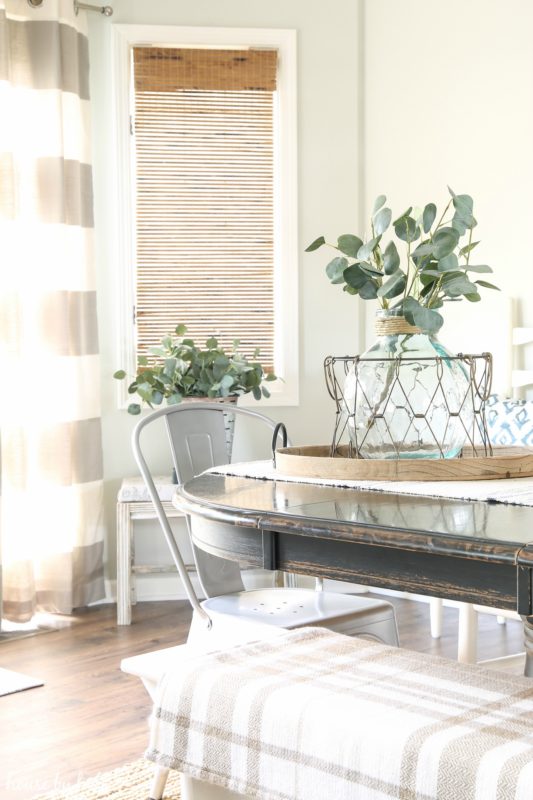 A throw blanket is on the bench of the dining room table.