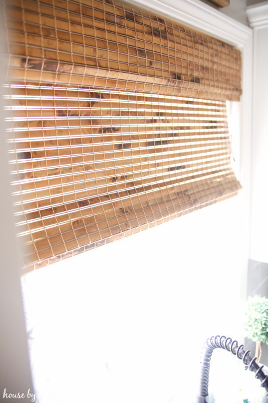 The woven blinds in the kitchen behind the sink.