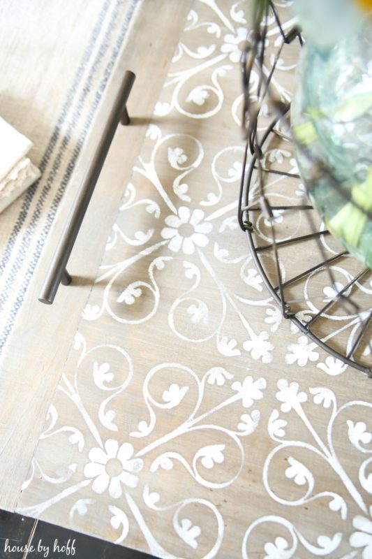 Aerial view of the white stencil, and metal handles on the serving tray.