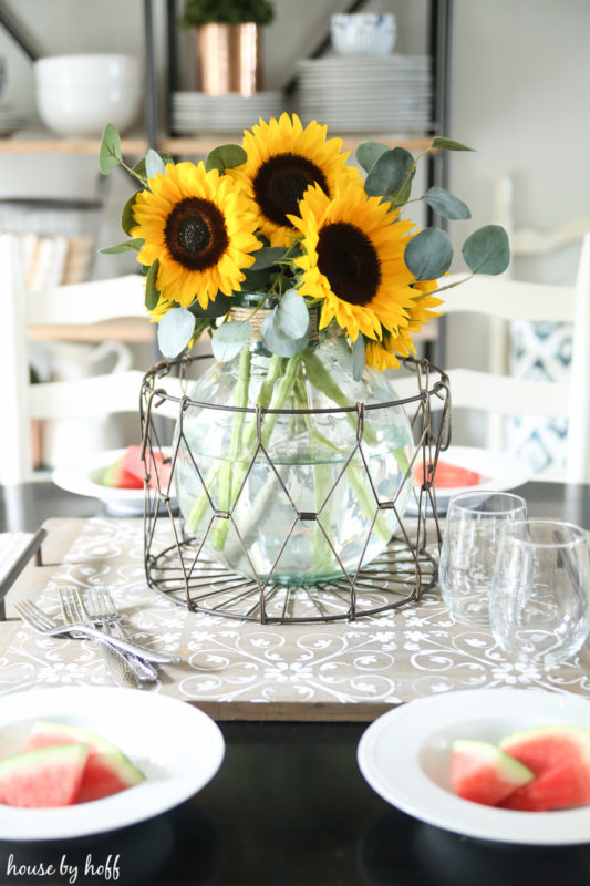 Sunflower and eucalyptus in vase on dining table.