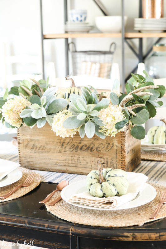 Faux green plants in wooden box on kitchen table.