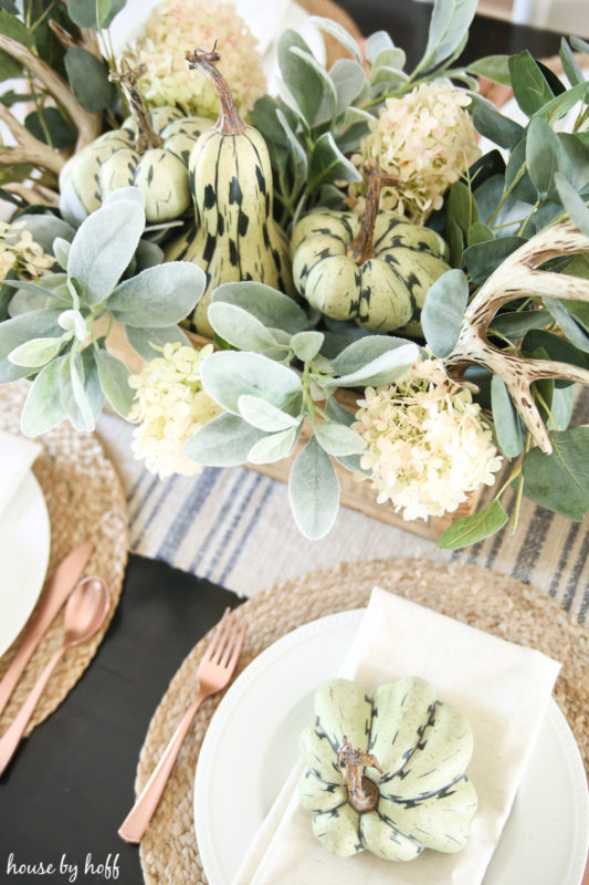 Greenery centerpiece with gourds, antlers, flowers, and eucalyptus.