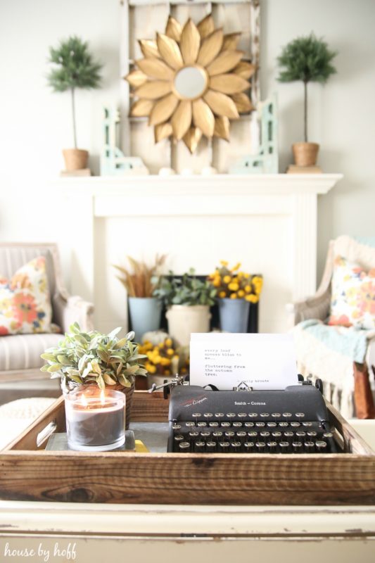 Black typewriter in wooden tray in living room.