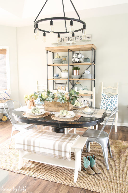 Dining room table with cowboy boots beside it, and a checkered blanket on the bench.