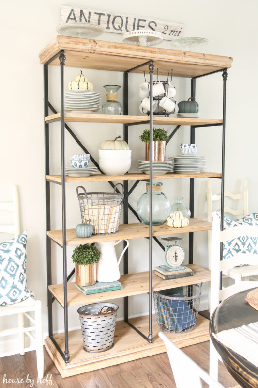 Open shelving unit behind the dining room table filled with collectibles.