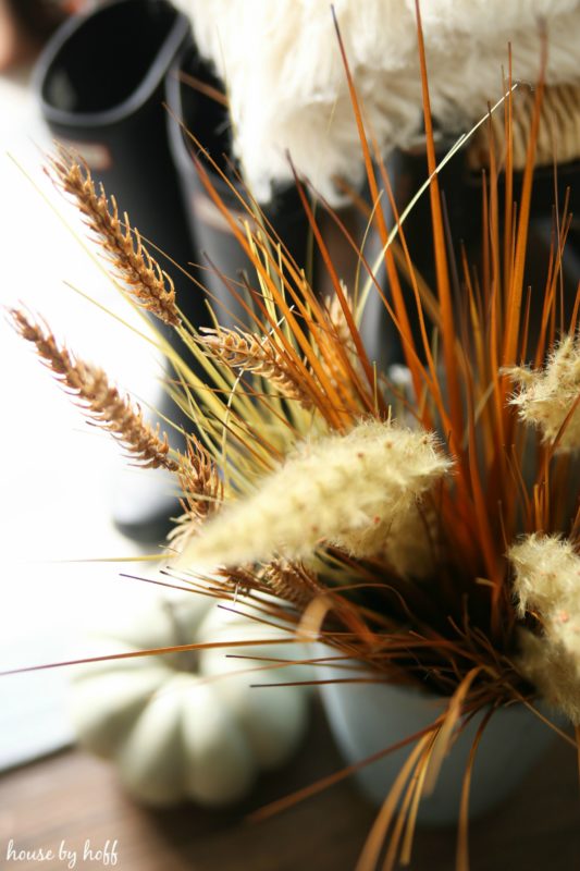 Stalks of light colored grass in large vase, in fall entryway.