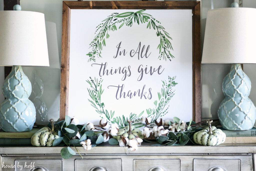 Framed In All Things Give Thanks poster on the pewter side table.